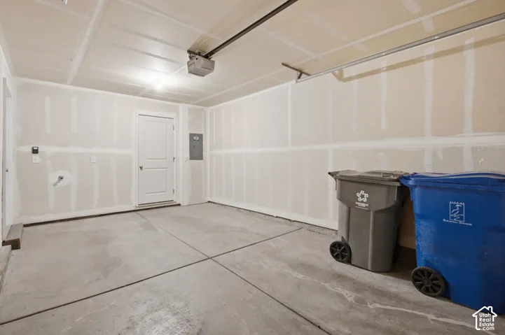 Concrete flooring with expansion joints, overhead lighting, and an overhead door opener mechanism