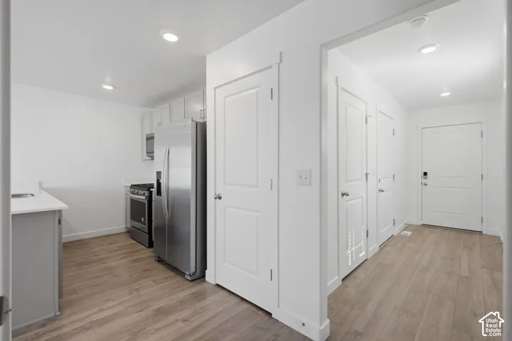 Kitchen featuring stainless steel appliances, light-toned cabinetry, light countertops, and wood-finish flooring