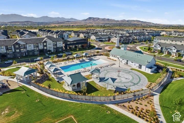 Expansive community grounds featuring a swimming pool, shaded seating areas, a central circular paved area, and manicured green spaces
