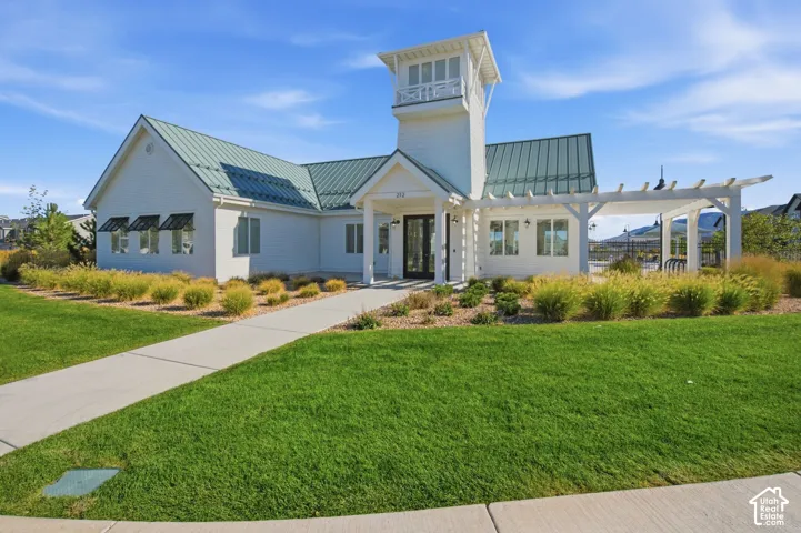 White exterior with a green metal roof, featuring a prominent cupola