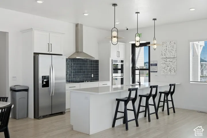 Kitchen featuring stainless steel appliances, white cabinetry, a large kitchen island, and contemporary pendant lighting