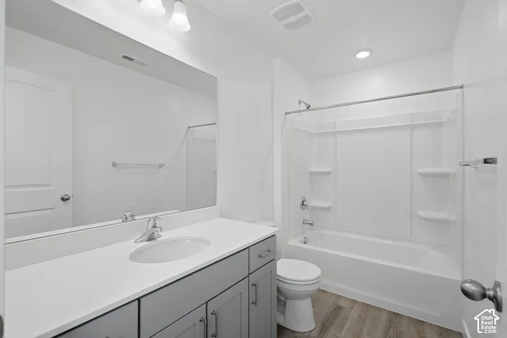 White vanity with a single basin sink, light-toned countertop, and chrome faucet