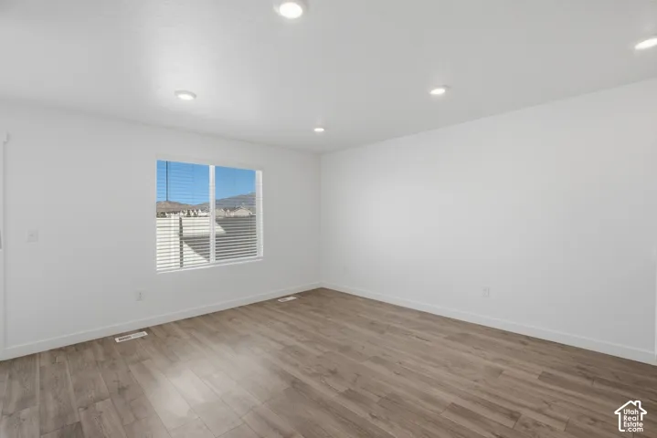 Wood-finish flooring, recessed lighting, and a large window with blinds