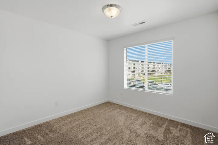 Bright room featuring a flush-mount ceiling light, white walls, and plush carpet flooring