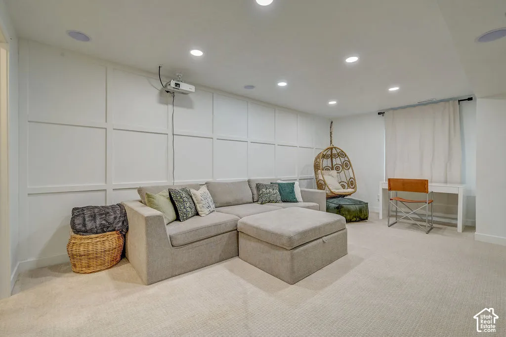 Recessed lighting illuminates a spacious room featuring wall paneling and neutral carpeting