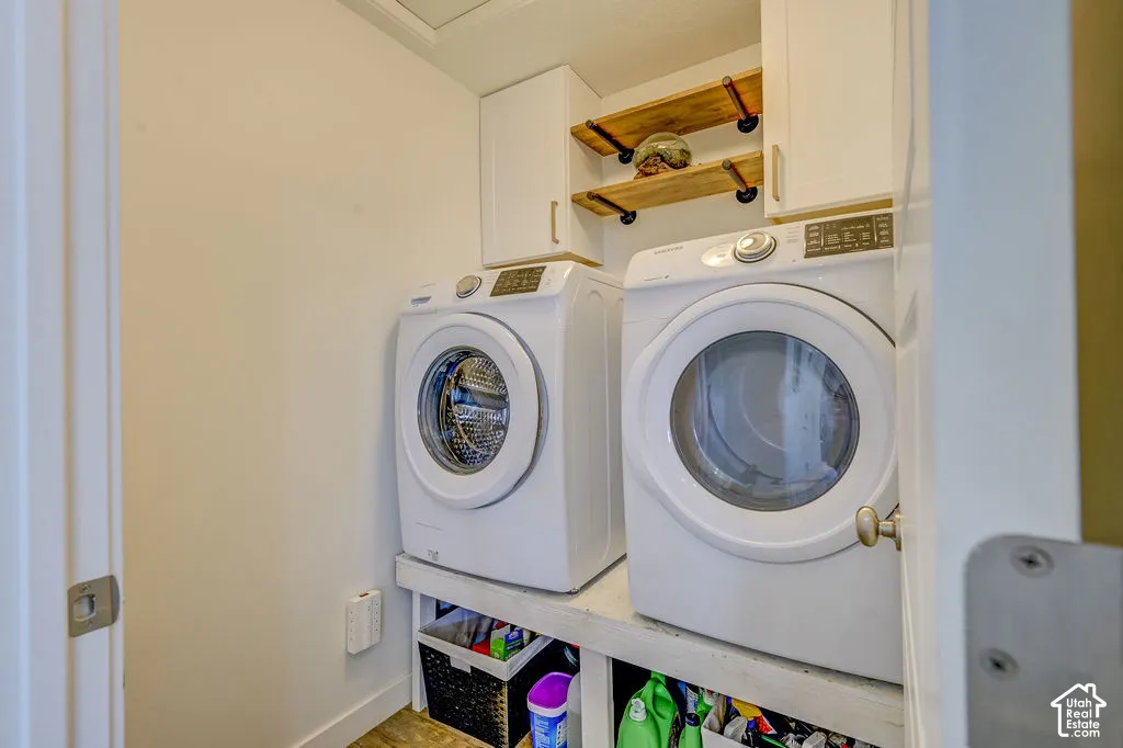 Dedicated laundry area featuring white cabinetry, two wood-finish floating shelves, and a built-in wood-finish platform