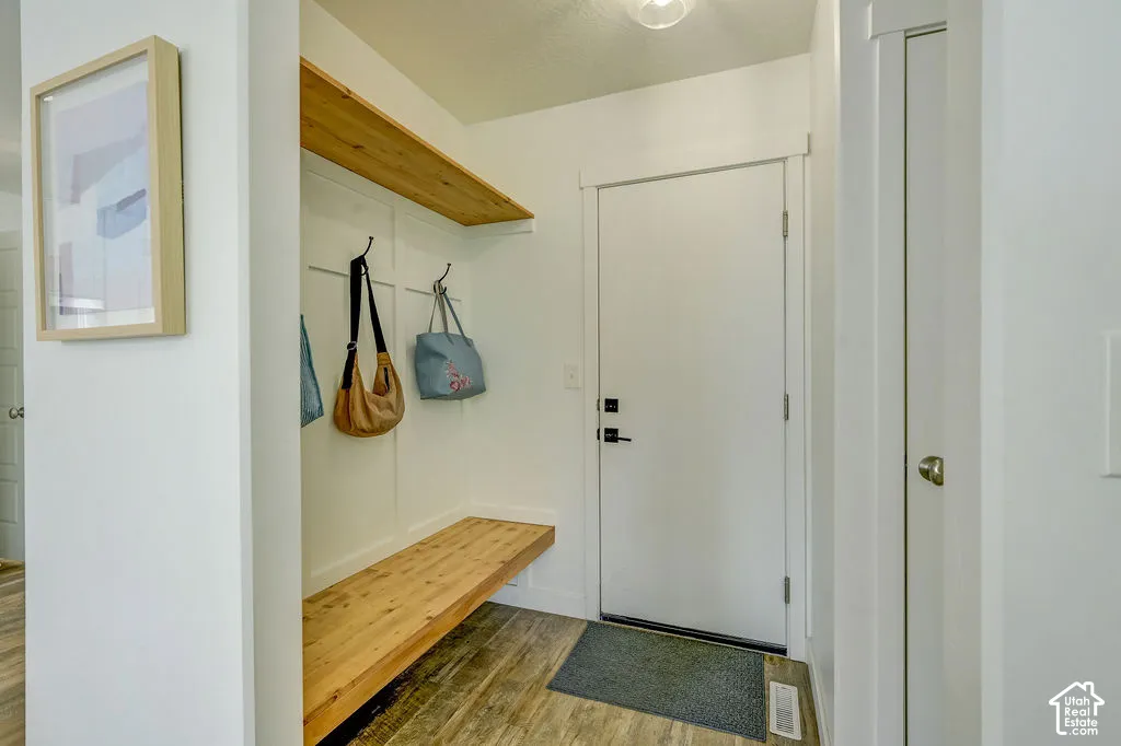 Built-in wood-finish bench with upper shelving and coat hooks, wood-finish flooring, and crisp white trim