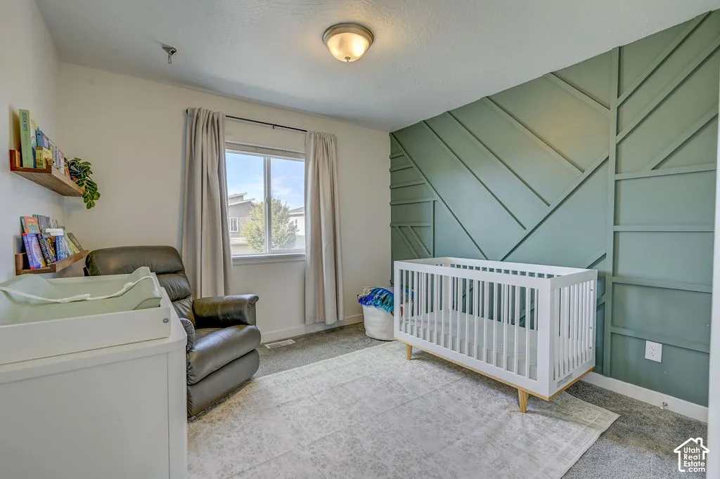 Accent wall with geometric wood trim, flush mount ceiling light fixture, window with drapes, and carpeted flooring