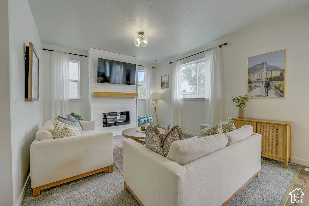 Living space featuring a shiplap fireplace with a wood mantel, a wall-mounted television, and a ceiling-mounted light fixture
