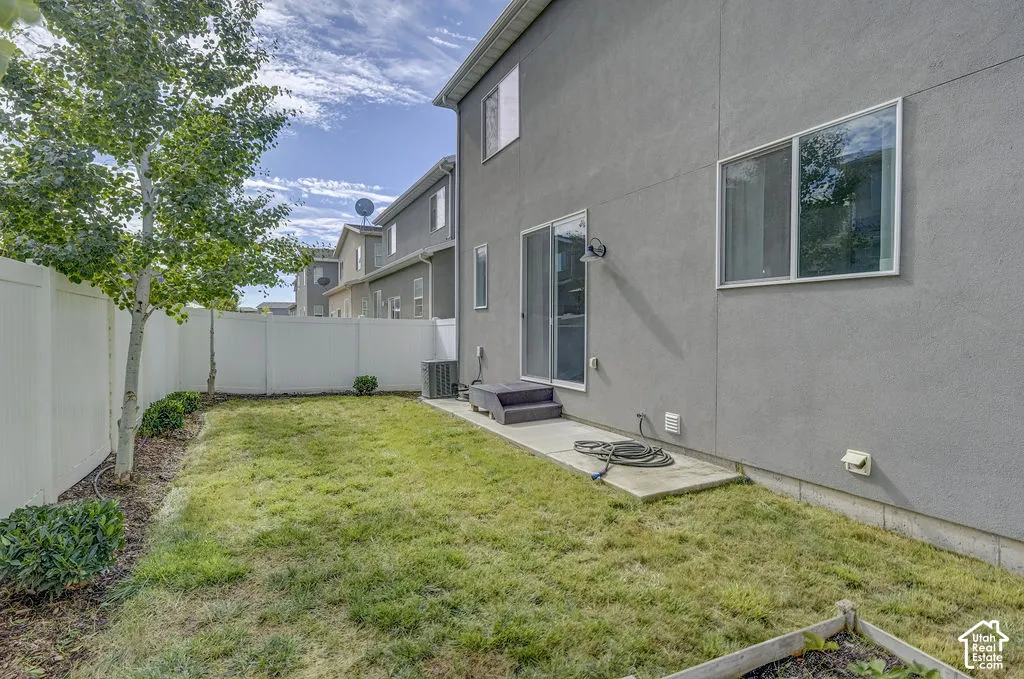 Backyard featuring a privacy fence, established trees, and a sliding glass door leading to a concrete patio
