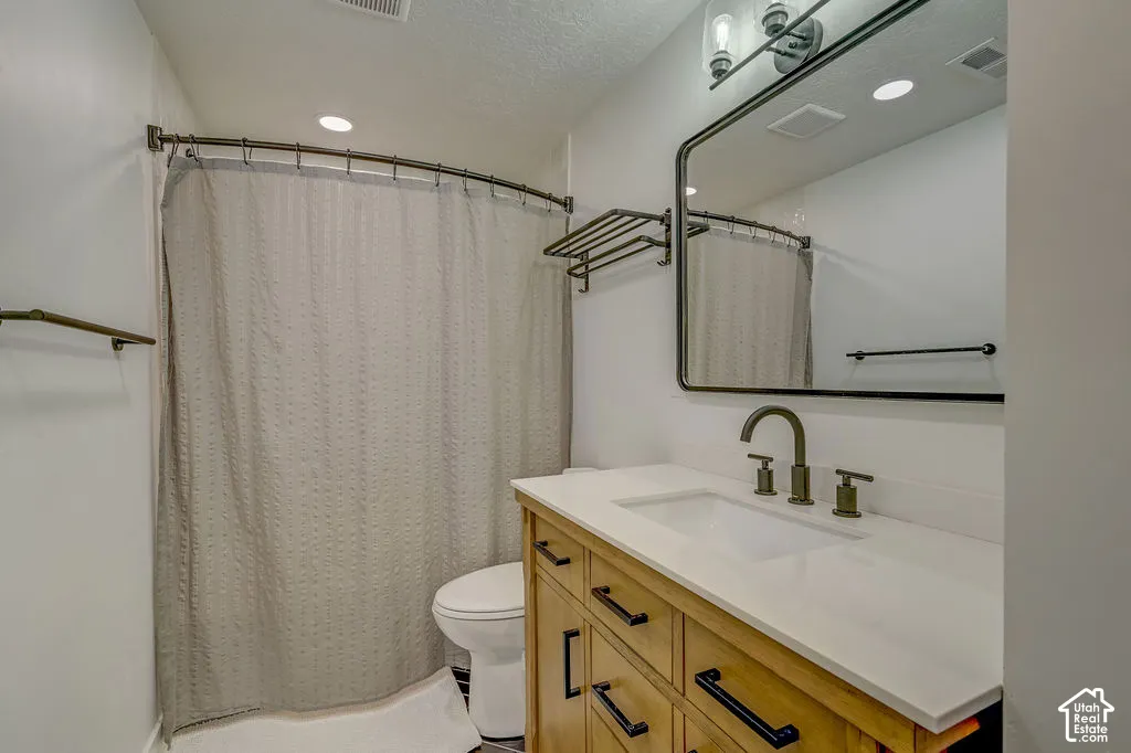 Bathroom featuring a wood-finish vanity with a white countertop, an integrated sink, and an arched black-framed mirror