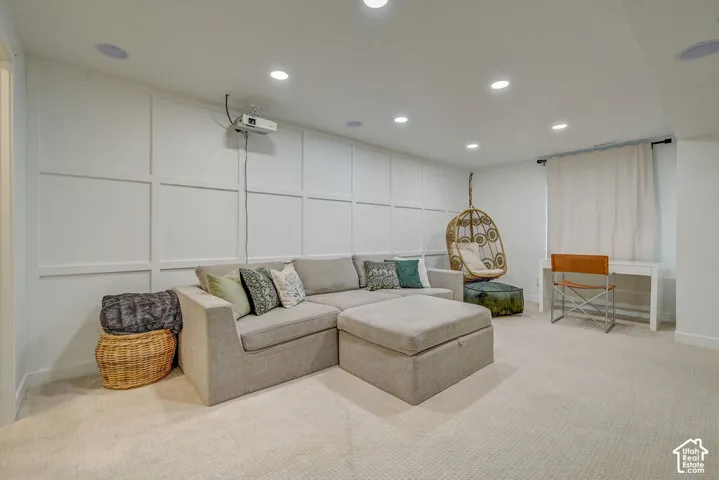 Recessed lighting illuminates a spacious room featuring wall paneling and neutral carpeting