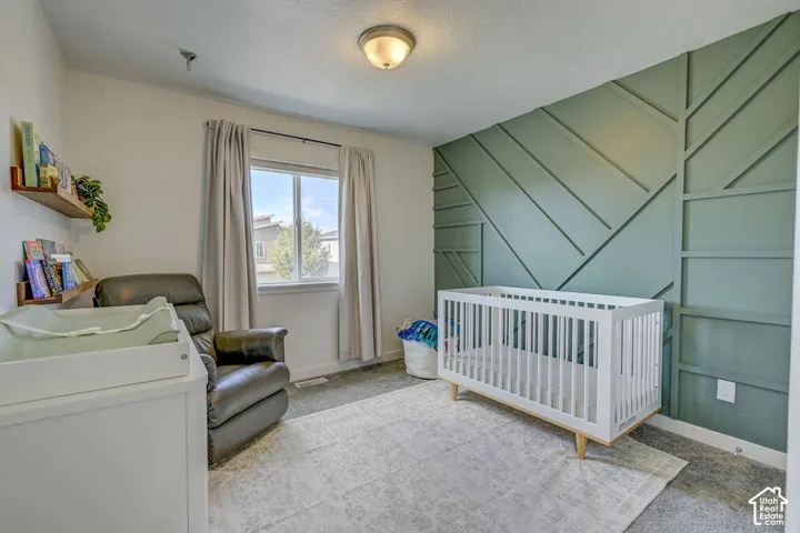 Accent wall with geometric wood trim, flush mount ceiling light fixture, window with drapes, and carpeted flooring