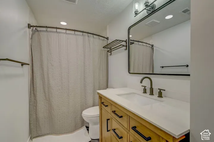 Bathroom featuring a wood-finish vanity with a white countertop, an integrated sink, and an arched black-framed mirror