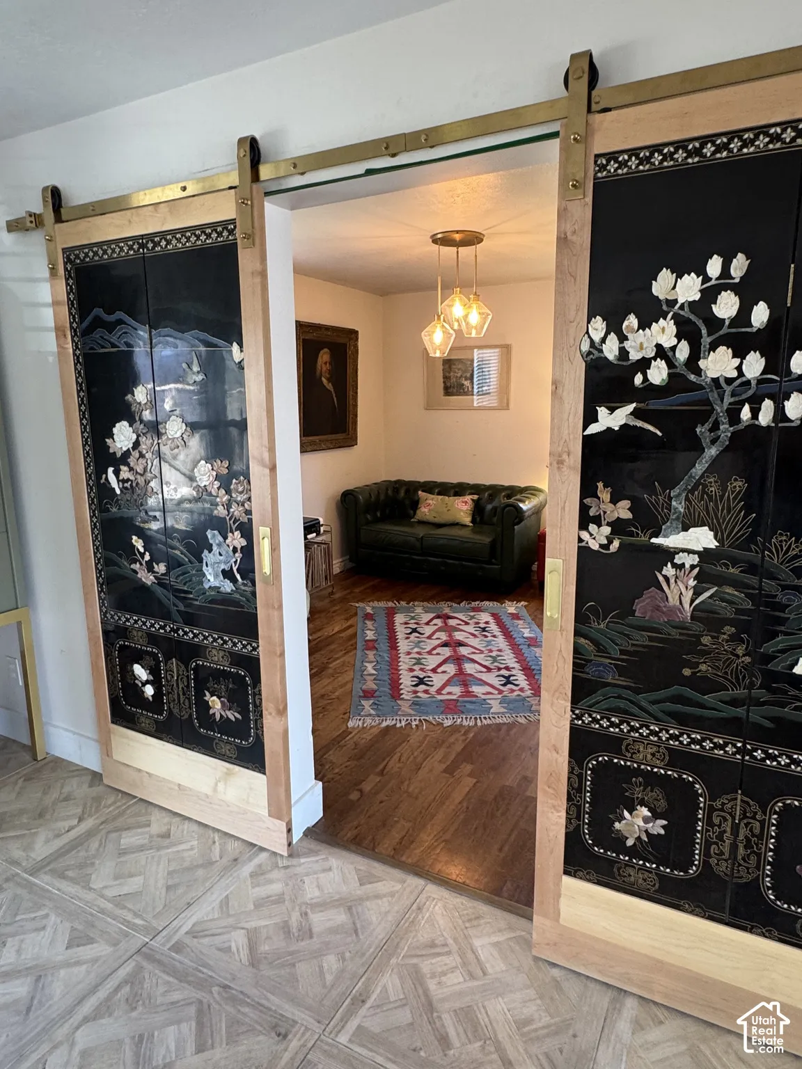 Vintage Asian barn doors with brass hardware, patterned floor tile, and original hardwood flooring