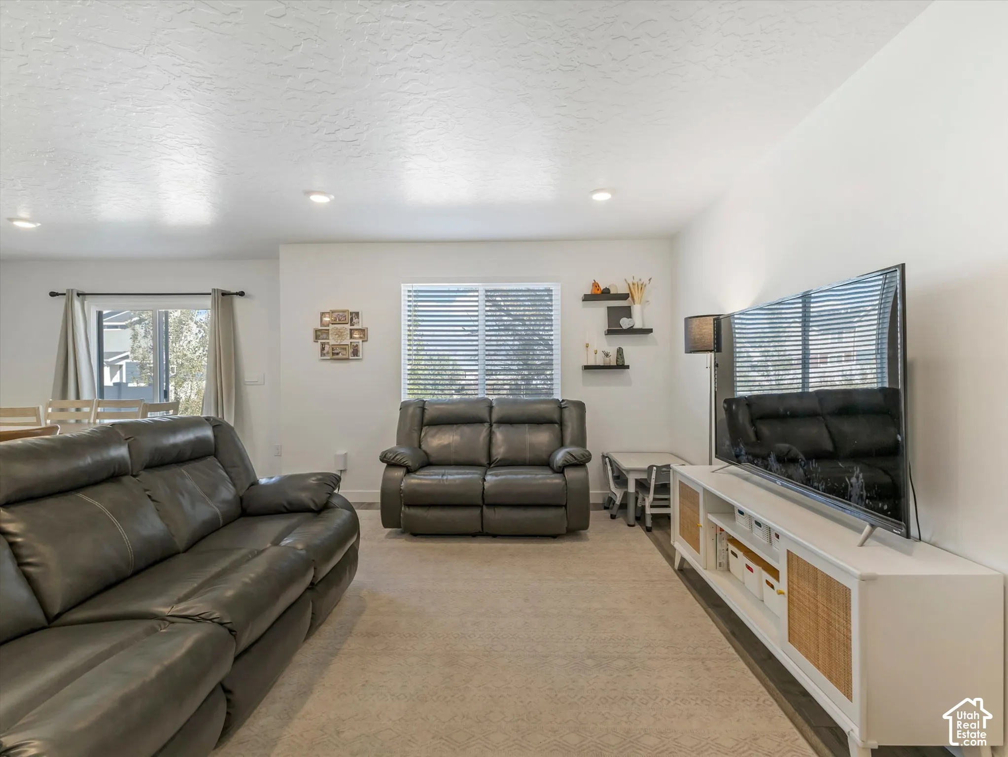 Recessed ceiling lighting illuminates a spacious living area featuring light-colored carpeting