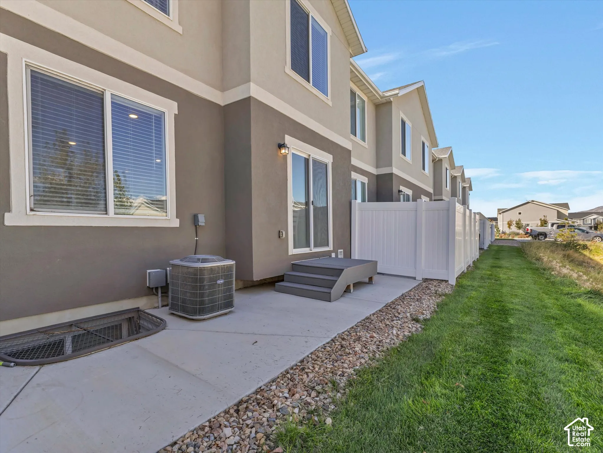 Concrete patio with gravel border, artificial wood steps, and white privacy fencing