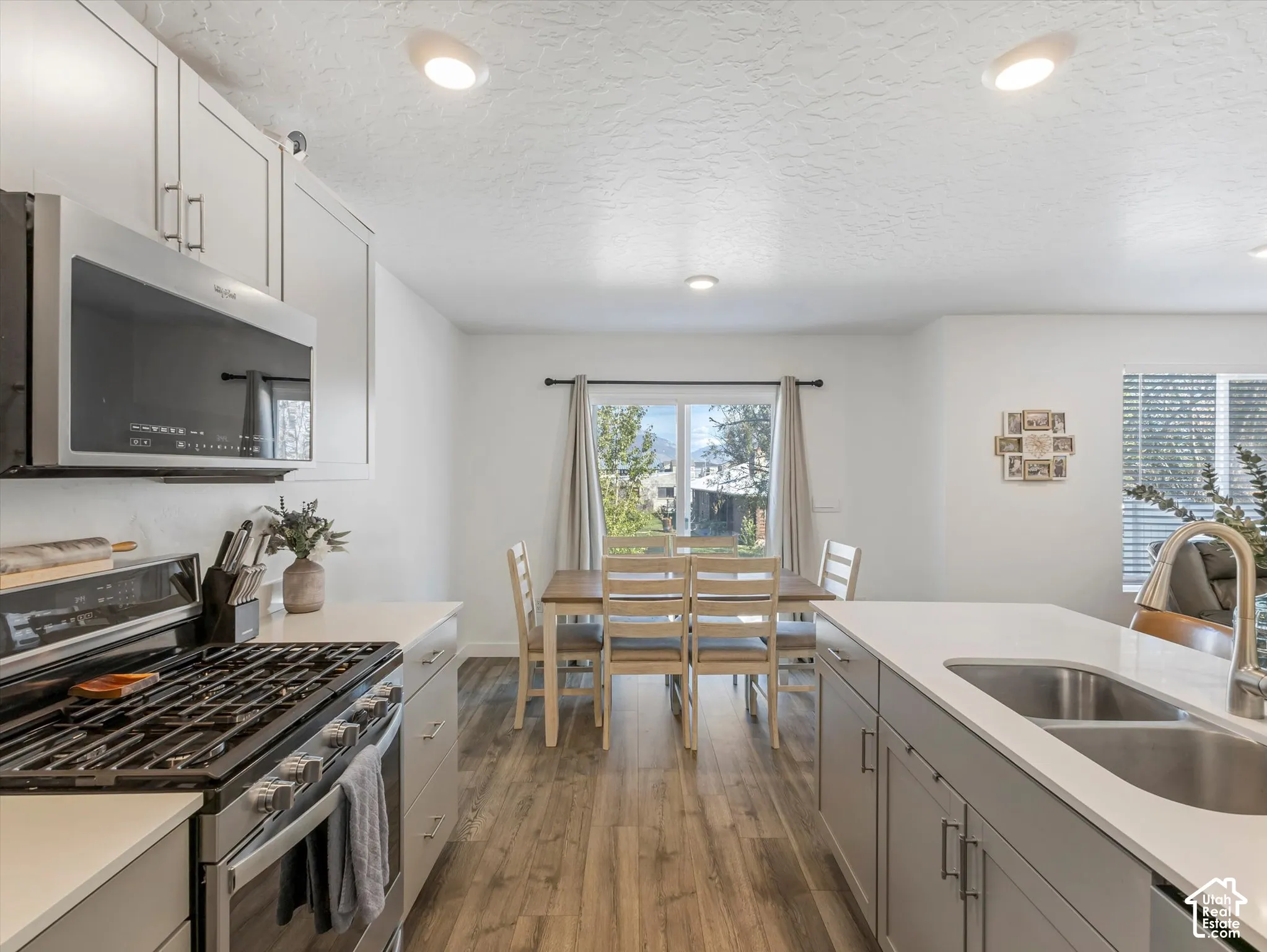 Kitchen featuring stainless steel appliances, light gray cabinetry, light countertops, wood-finish flooring, and recessed lighting