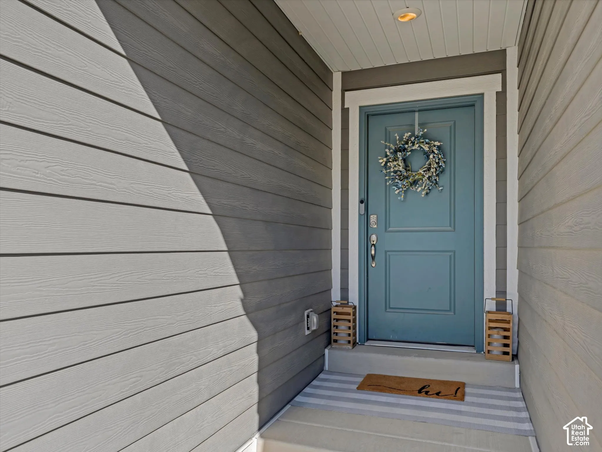 Horizontal siding exterior with a contrasting entry door, white trim, and a recessed overhead light