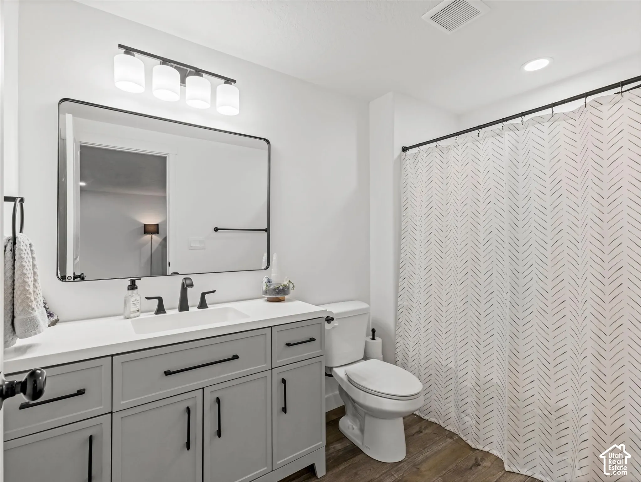 Light gray vanity with black hardware, white countertop, rectangular undermount sink, and black-finish faucet