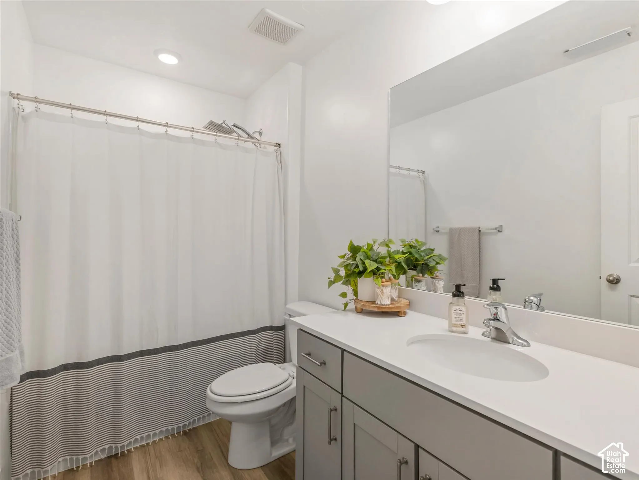 Bathroom featuring a vanity with a white countertop and undermount sink, built-in cabinetry, and wood-finish flooring