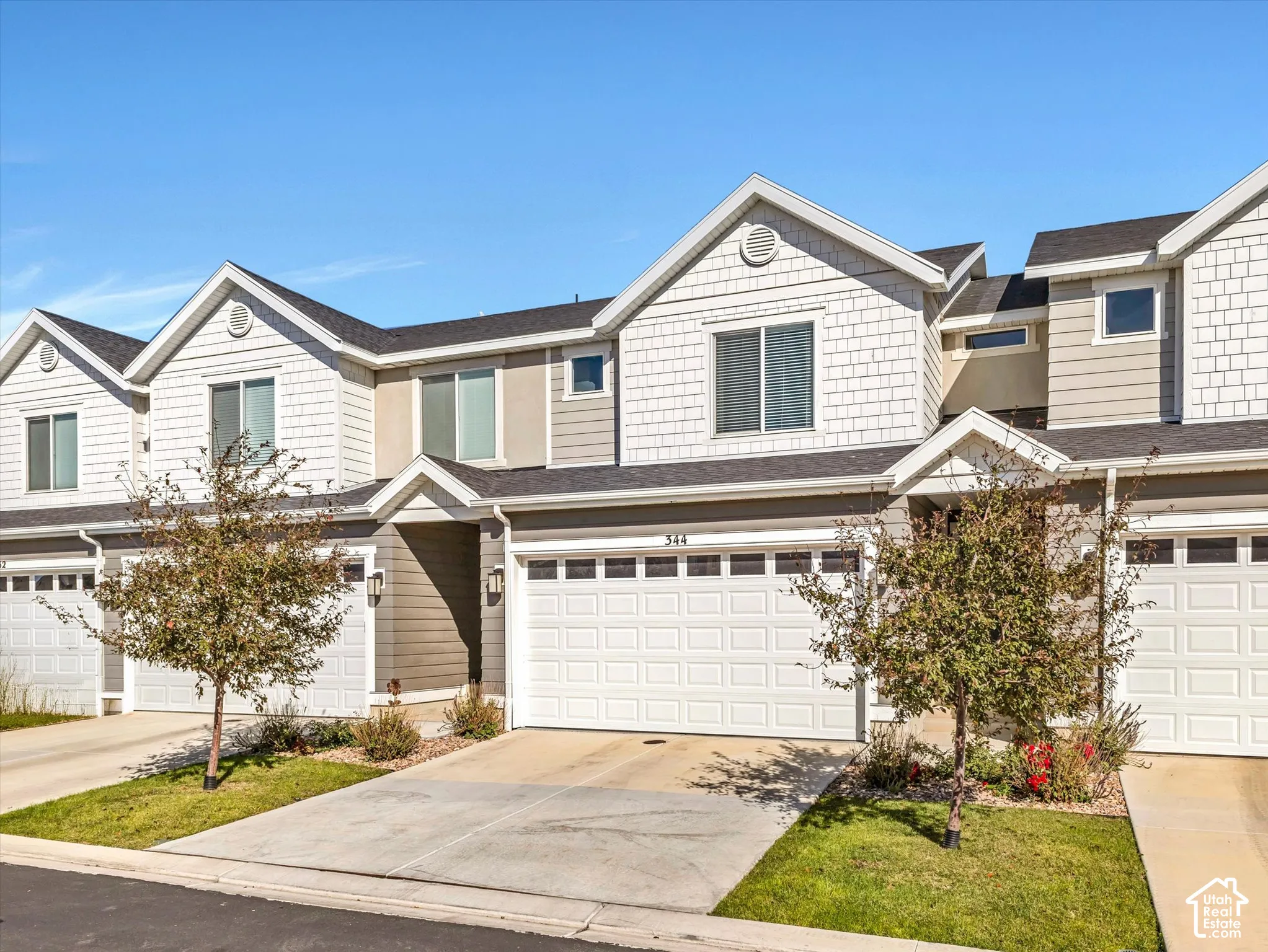 Multi-level townhome featuring a two-car garage, partial shake siding, and gabled rooflines