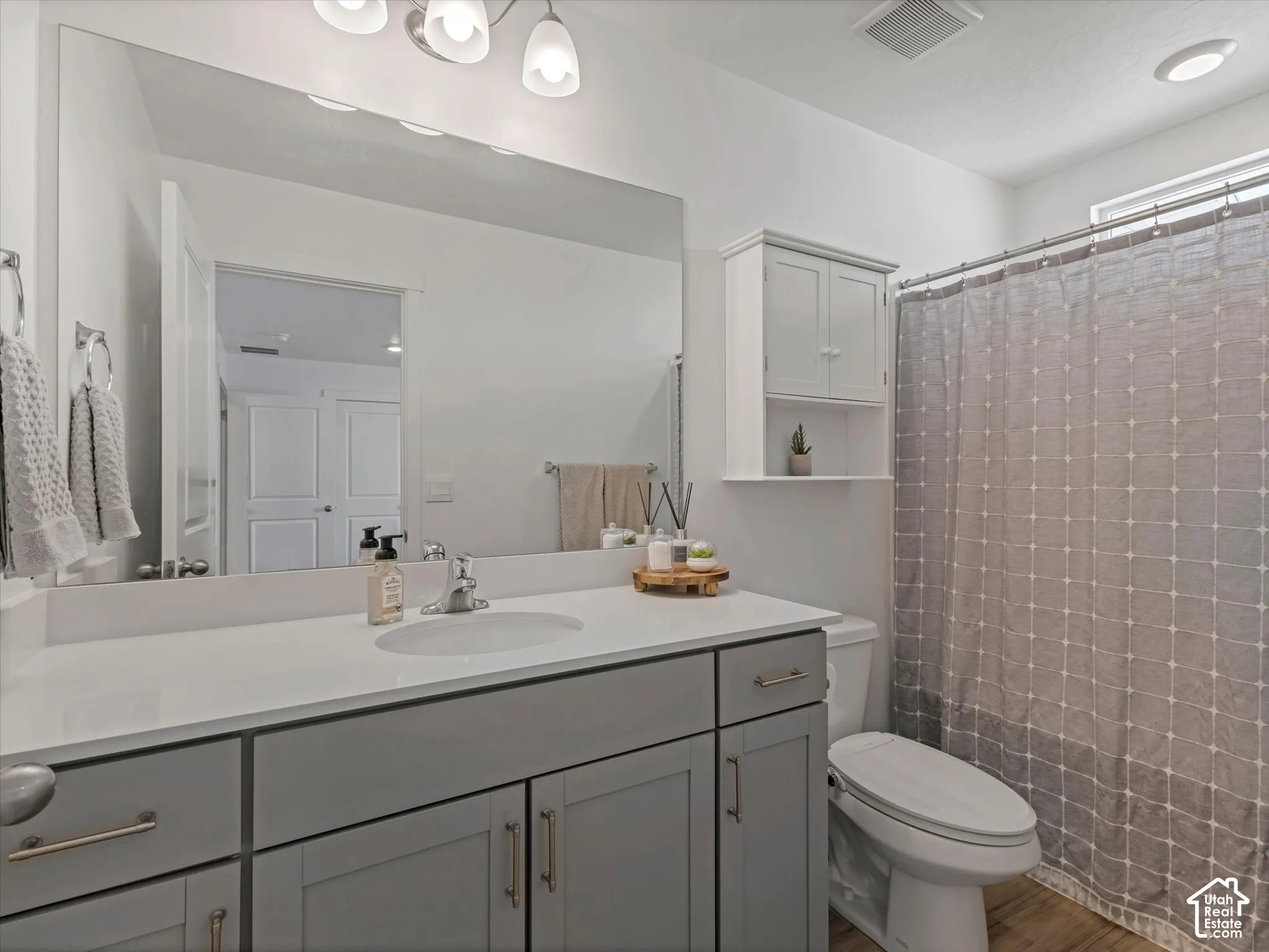 Spacious vanity with a light gray cabinet and white countertop, undermount sink, and a large wall-mounted mirror