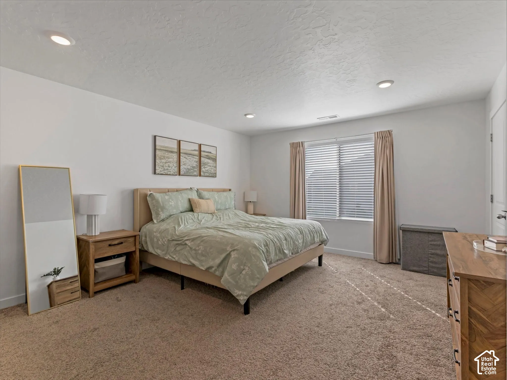 Recessed ceiling lighting, a large window with blinds and drapes, and neutral-toned wall-to-wall carpeting
