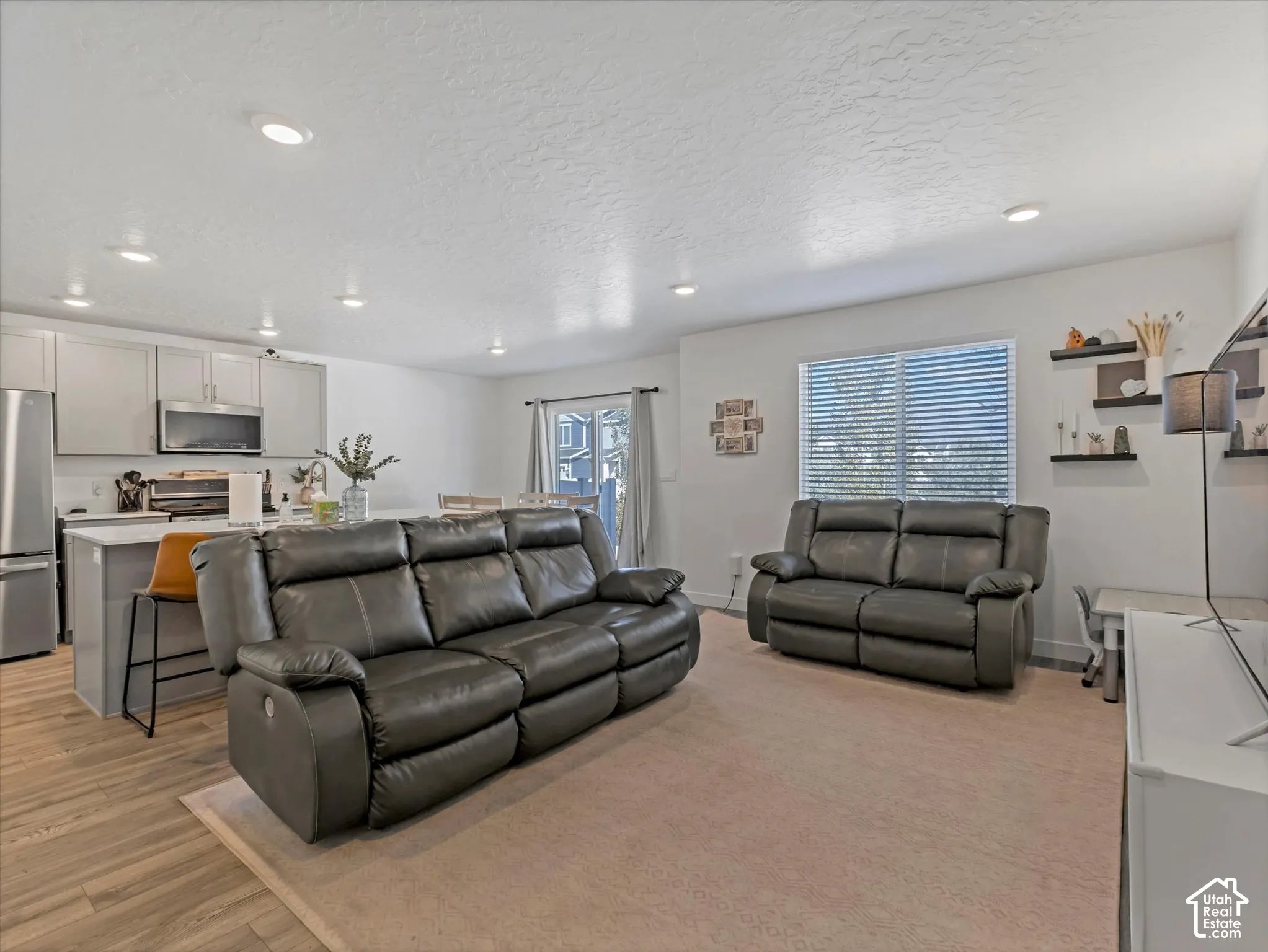 Open-concept living area with recessed lighting, wood-finish flooring, and a kitchen island with seating