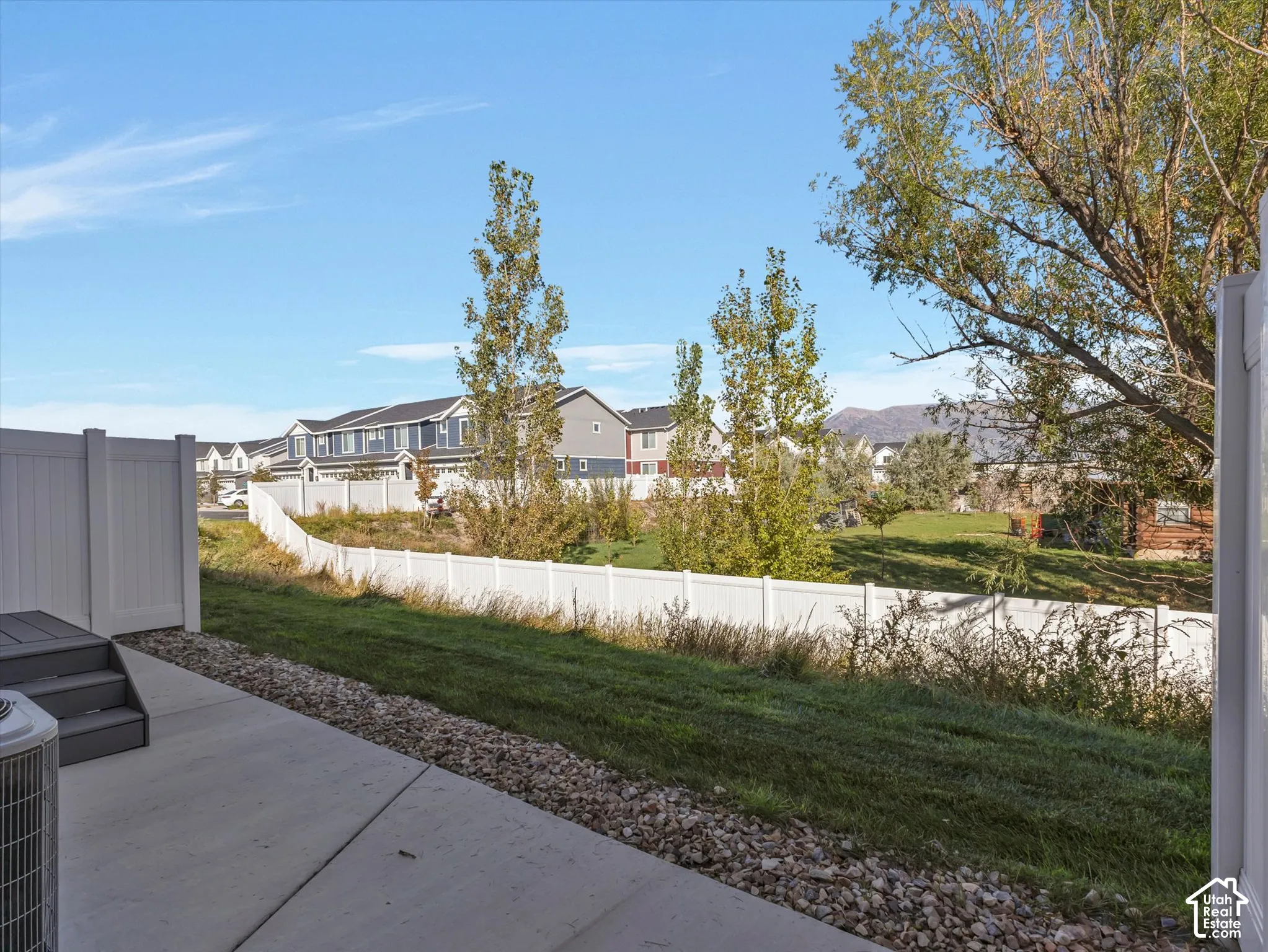 Concrete patio with an adjacent gravel border, leading to a lawn area
