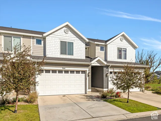 Modern townhome exterior with mixed siding, attached garage, and paved driveway