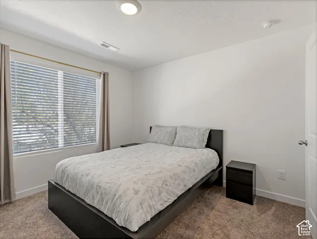Neutral-toned carpeting paired with white walls, a single window with blinds, and an overhead flush-mount light fixture
