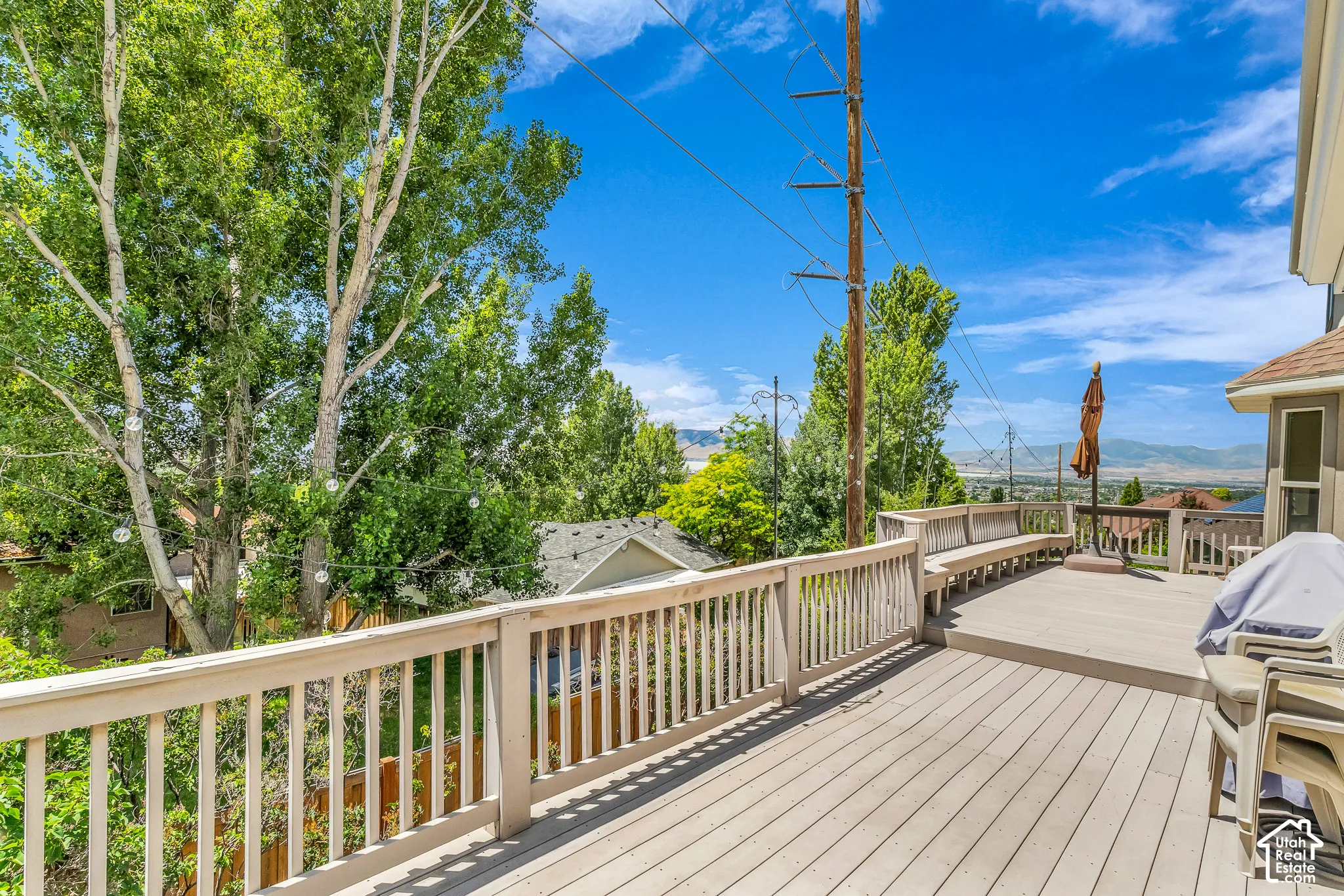 Expansive outdoor deck with integrated bench seating, light-toned wood-finish decking, and light-colored railing