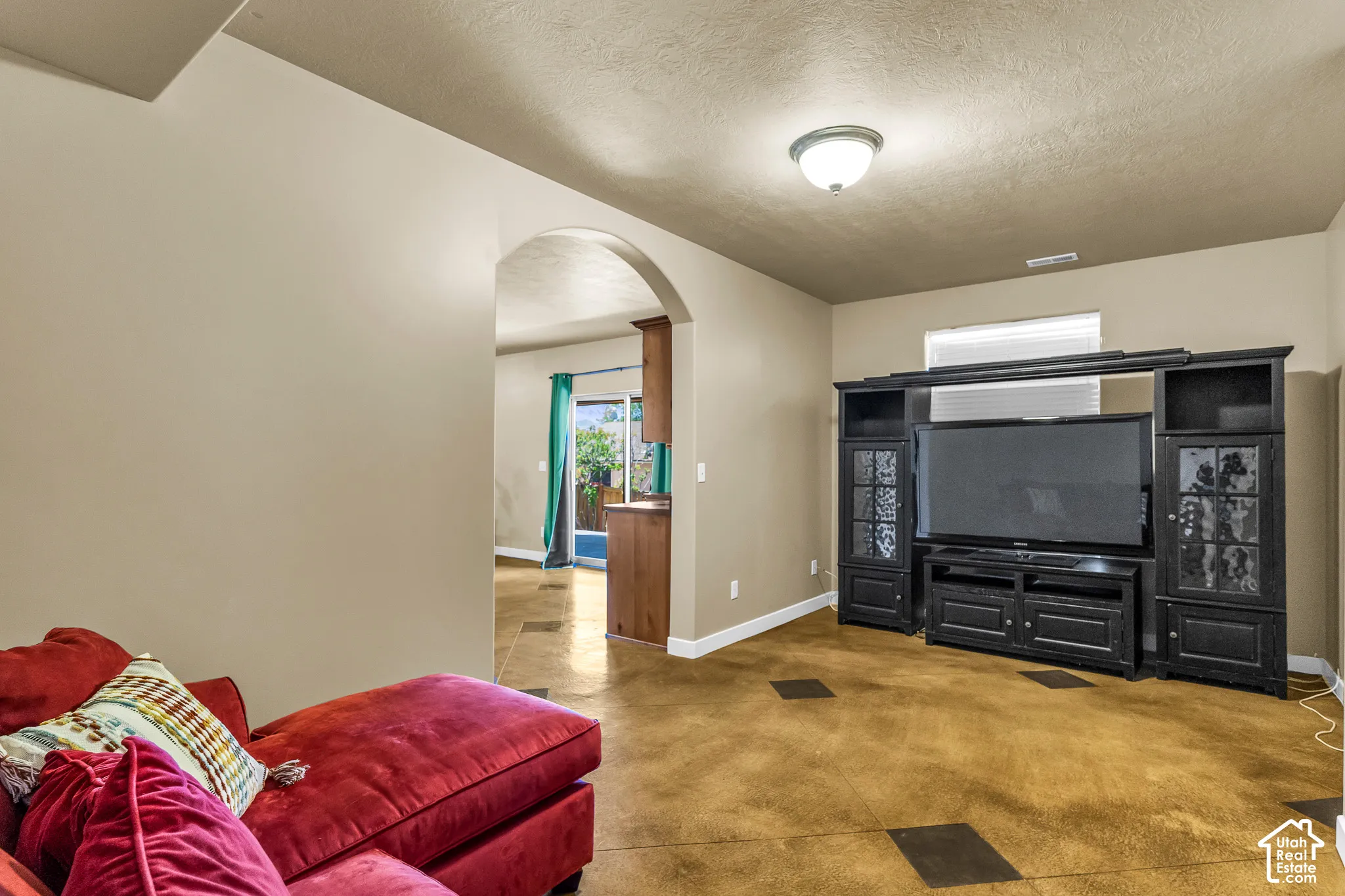Archway entry, stained concrete flooring, recessed window, and flush mount lighting