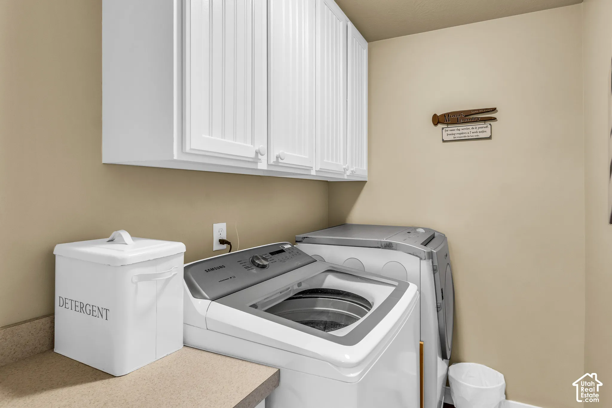 White shaker-style cabinetry, neutral countertop, and wall-mounted electrical outlet