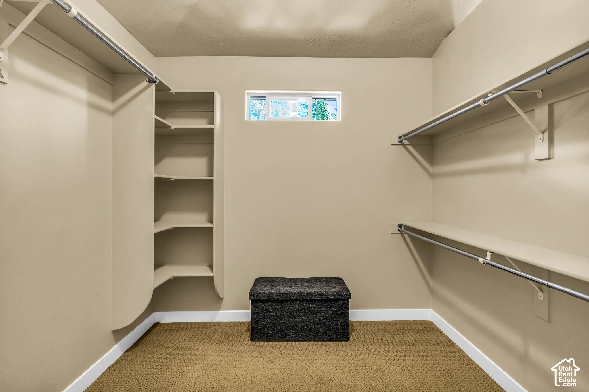 Expansive walk-in closet featuring built-in shelving, multiple hanging rods, and a high-set window