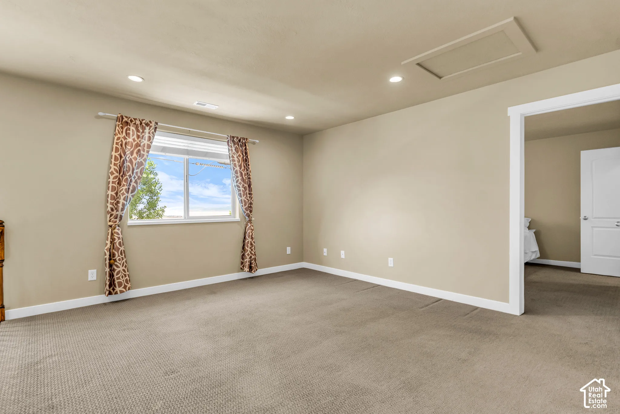 Recessed lighting, tan wall paint, white trim, carpeted flooring, and a single window