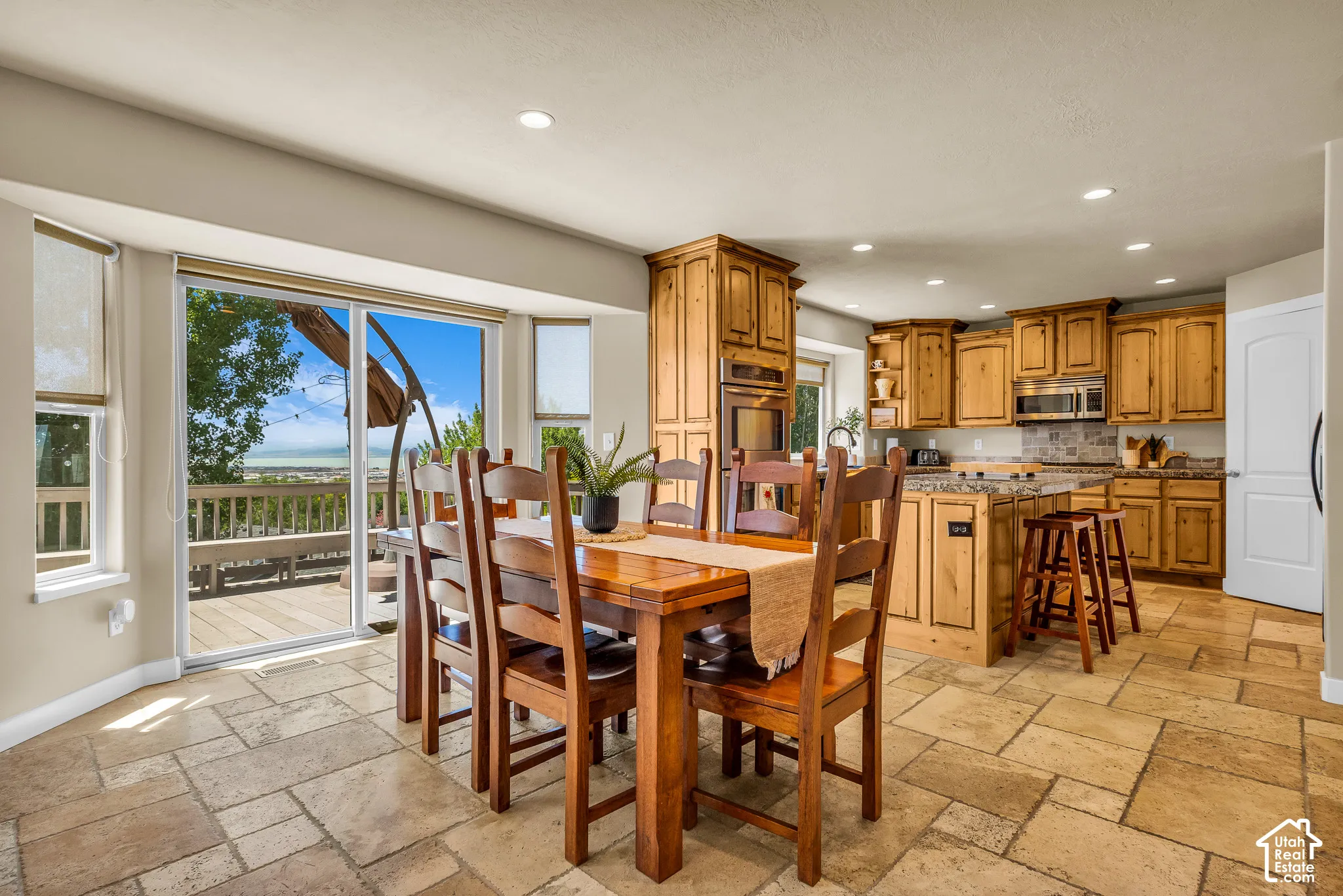 Kitchen and dining area featuring wood cabinetry, granite countertops, stainless steel appliances, and large format tile flooring