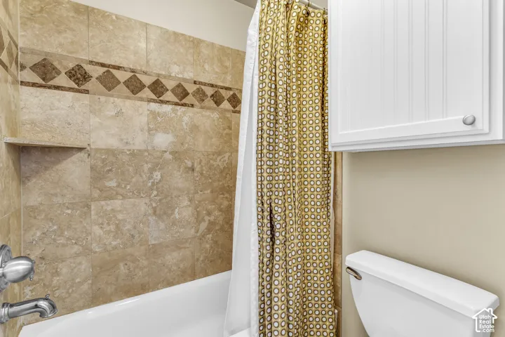 Bathtub with a tiled surround, decorative tile accent band, built-in shower niche, and polished chrome fixtures