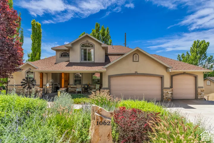 Stucco exterior with stone accents, covered front porch, arched windows, and an attached two-car garage