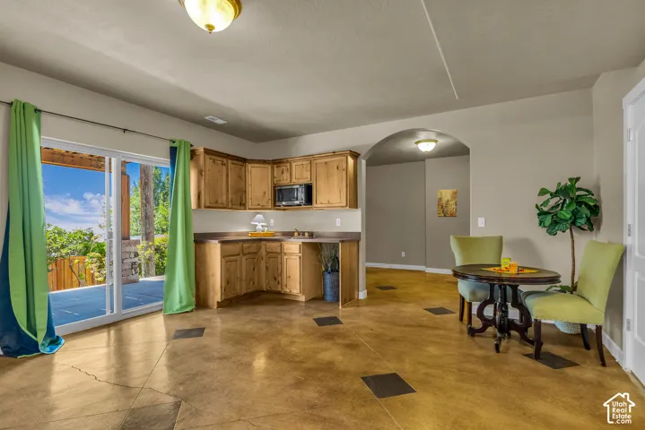 Wood-finish flooring with accent tiles, built-in cabinetry with a microwave, and a sliding glass door leading to an outdoor patio