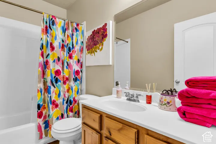 Bathroom featuring a vanity with wood-finish cabinetry, a single basin sink, and a framed mirror