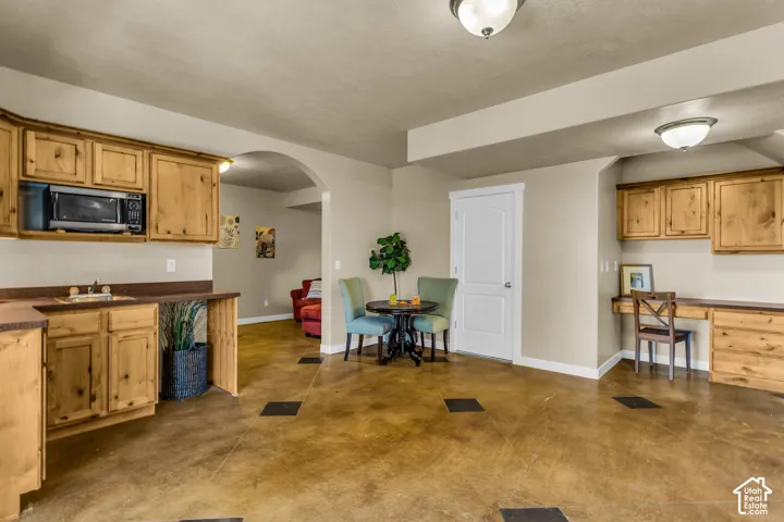 Stained concrete flooring, built-in desk, wood cabinetry, arched doorway, and a built-in wet bar