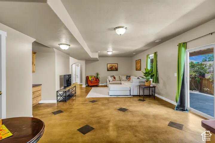 Spacious open-plan room with polished concrete flooring, recessed lighting, and a built-in wood-finish cabinet with a dark countertop