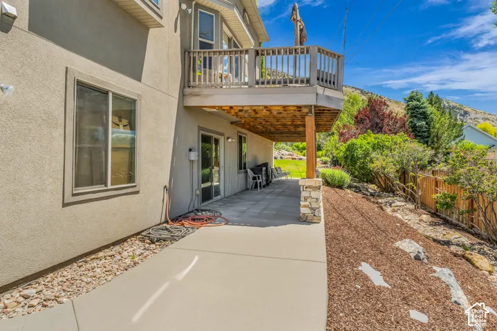 Exterior features stucco siding, a concrete patio, and a second-story wood deck