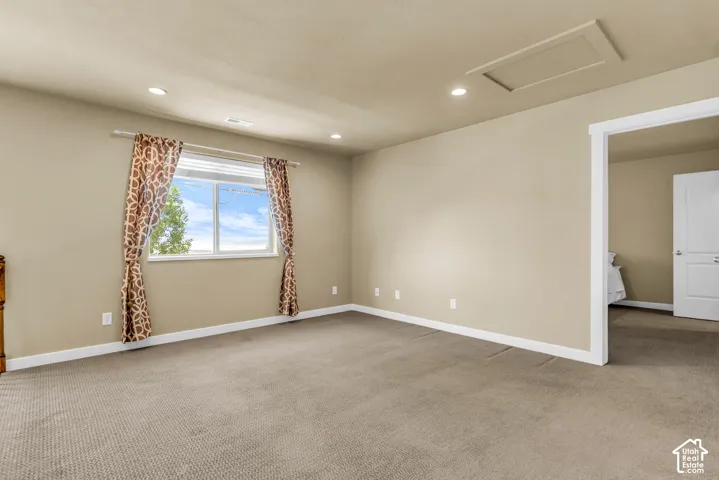 Recessed lighting, tan wall paint, white trim, carpeted flooring, and a single window
