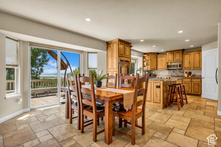 Kitchen and dining area featuring wood cabinetry, granite countertops, stainless steel appliances, and large format tile flooring