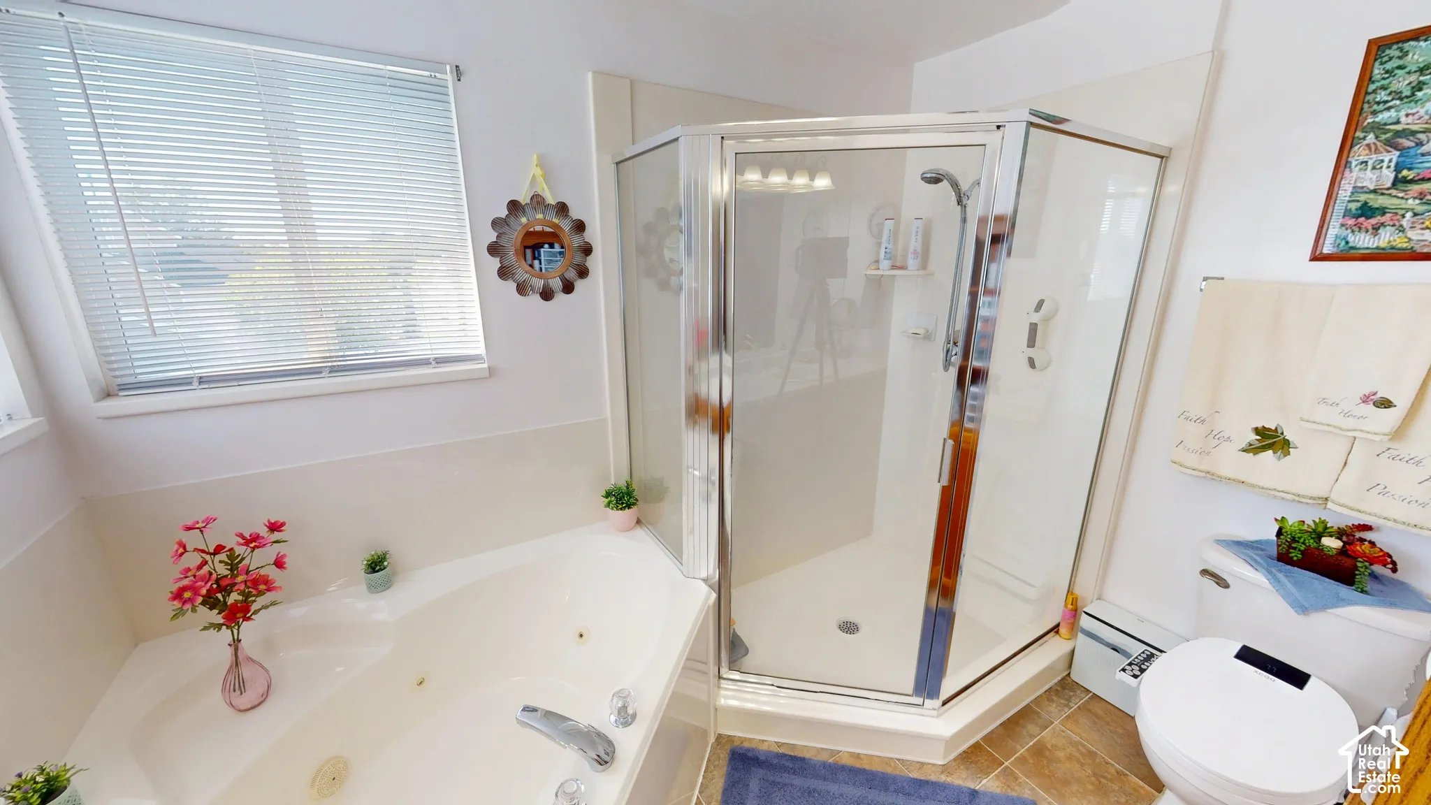 Corner soaking tub, enclosed glass shower, window with blinds, and tile flooring