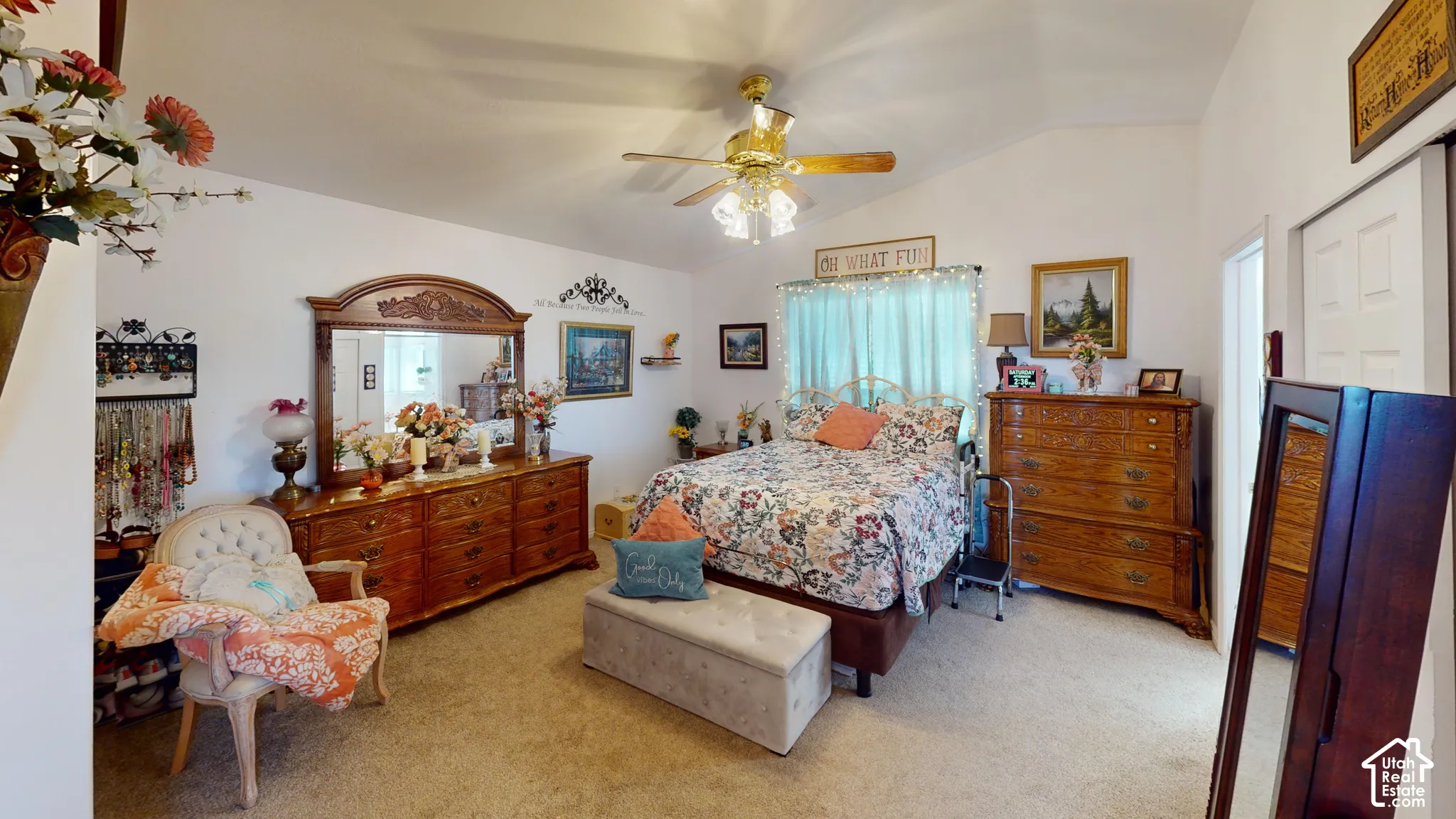 Vaulted ceilings, a ceiling fan with light fixture, and carpeted flooring