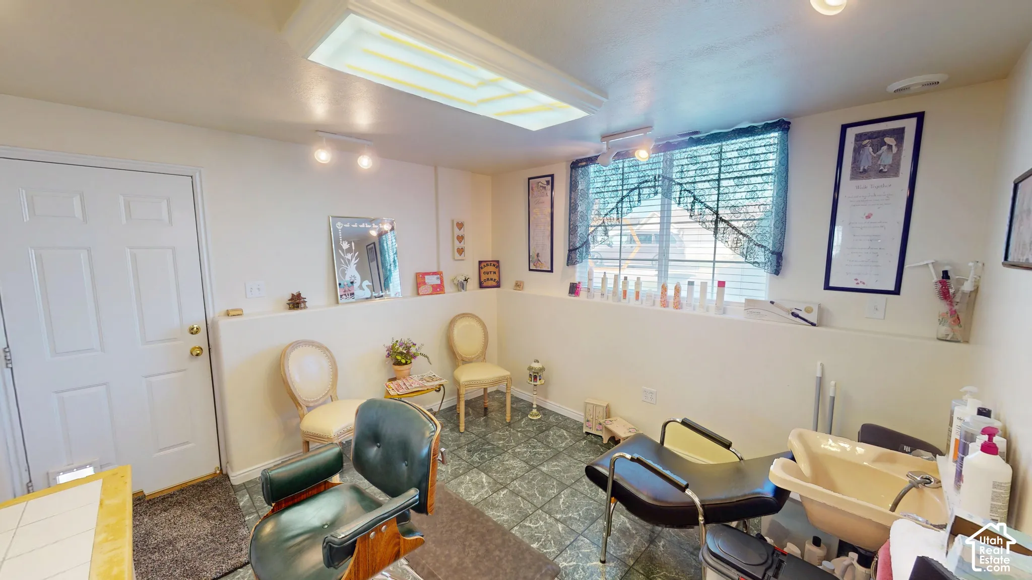 Recessed window with privacy blinds, track lighting, and a fluorescent ceiling fixture, complemented by green-hued tile flooring